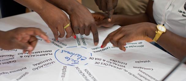 close up of several people's hands pointing to a diagram on a piece of paper
